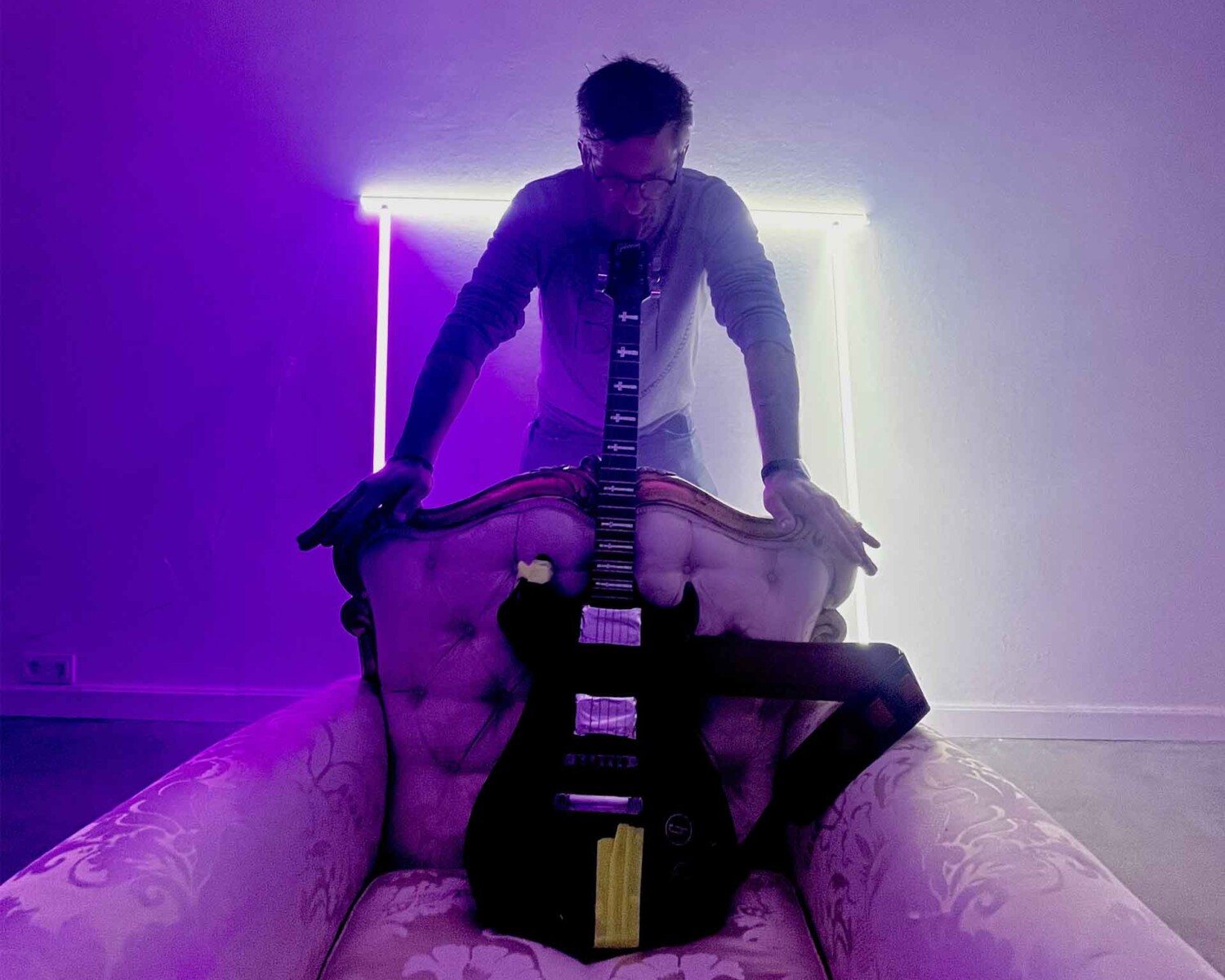 Hannes Schiefer mit E-Gitarre auf Möbel